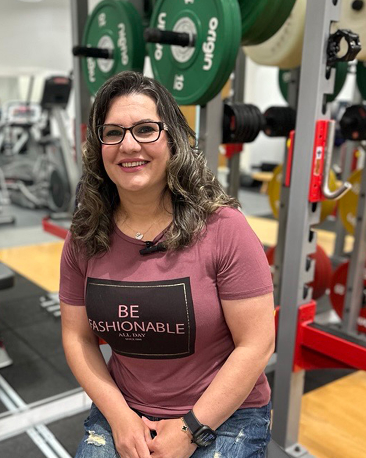 Ashti Ali sitting on a gym bench behind weights
