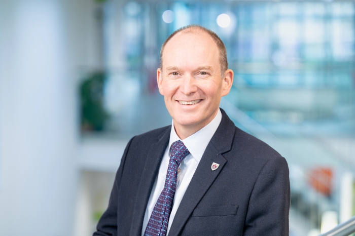 Roger Sendall, Deputy University Secretary, in formal business attire picture against a blue backdrop at An Lochran on Inverness Campus