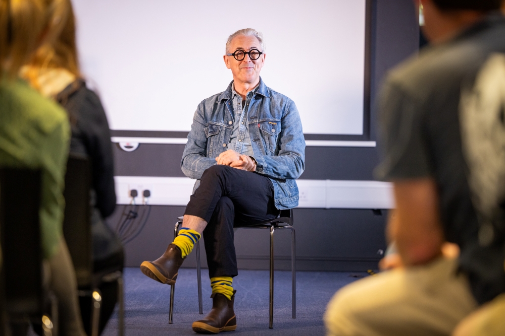 Alan Cumming sitting smiling