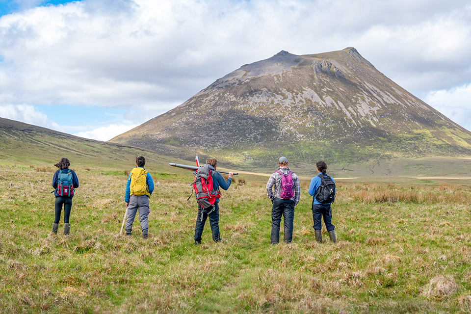 Five researchers standing in a field with research equipment Five researchers standing in a field with research equipment
