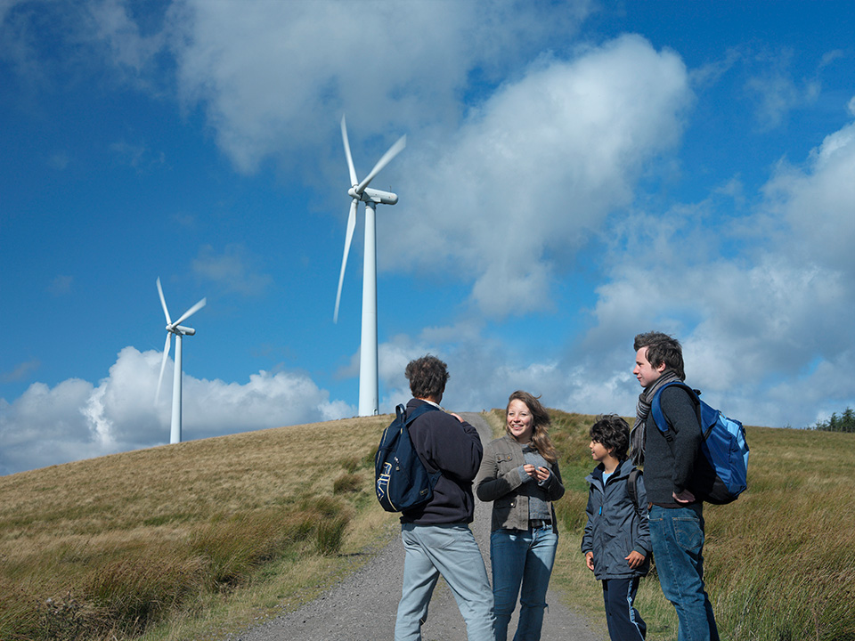 Four people standing in front of a wind turbine Four people standing in front of a wind turbine