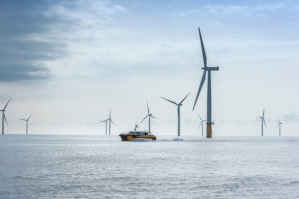 A boat sailing through an offshore windfarm A boat sailing through an offshore windfarm
