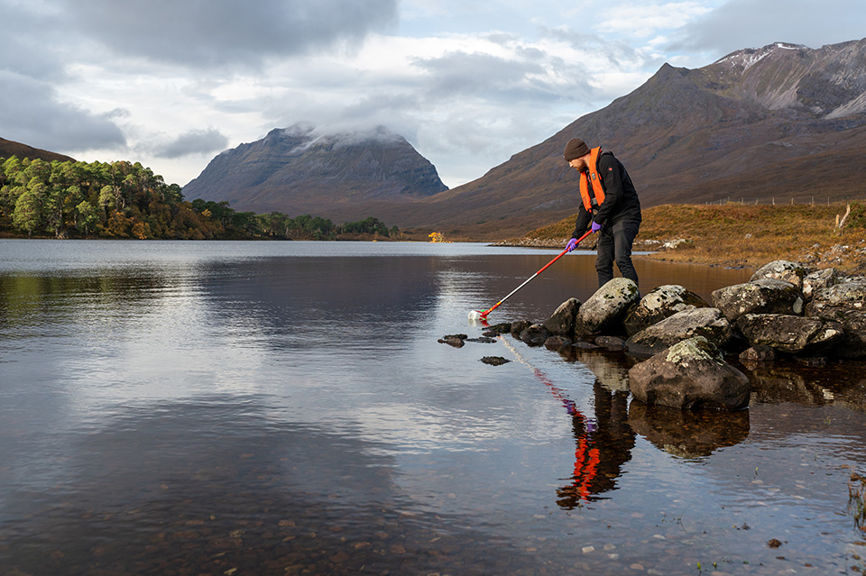 Person taking a water sample in a mountainous region Person taking a water sample in a mountainous region