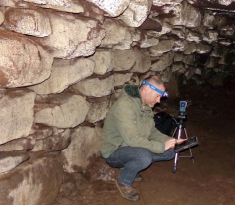 Person in a cave with audio equipment
