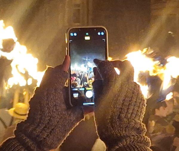 A photograph of someone taking a photograph of a burning ship at UpHellyYa A photograph of someone taking a photograph of a burning ship at UpHellyYa