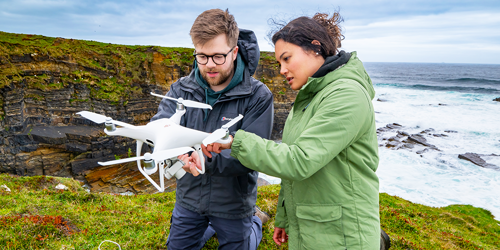 Two researchers examining a drone. Two researchers examining a drone.