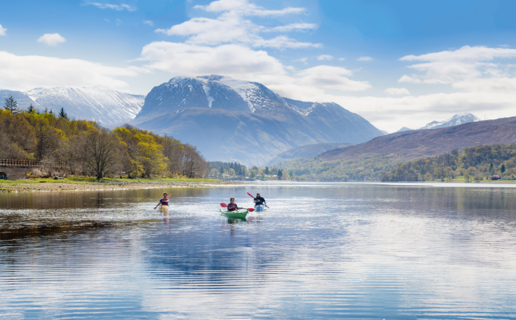 People kayaking with mountains in the background People kayaking with mountains in the background
